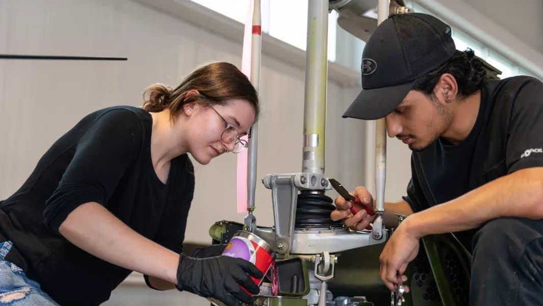 Estudiantes revisando el tren de aterrizaje de una aeronave en el hangar del Aviation Centre of Excellence de Confederation College