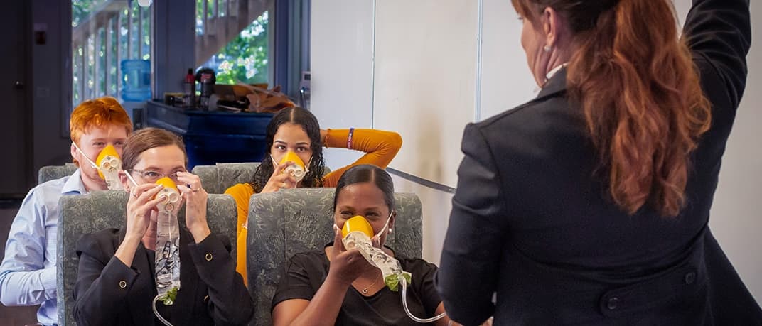 Estudiantes practicando el uso de máscaras de oxígeno de emergencia, programa de Atlantic Flight Attendant Academy