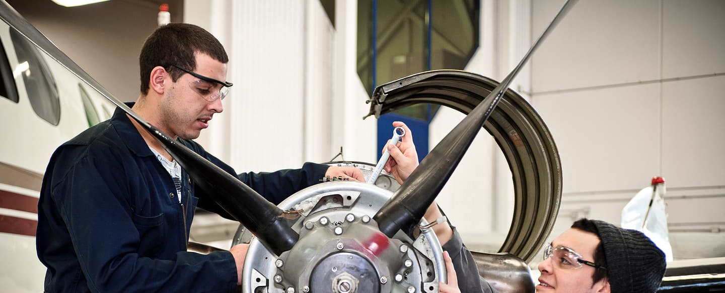 Estudiantes de Centennial College inspeccionando el motor de una aeronave en el laboratorio