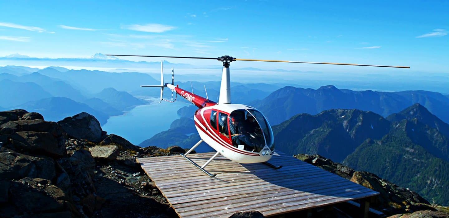 Helicóptero Robinson R44 de Chinook Helicopters posado en la cima de una montaña de BC
