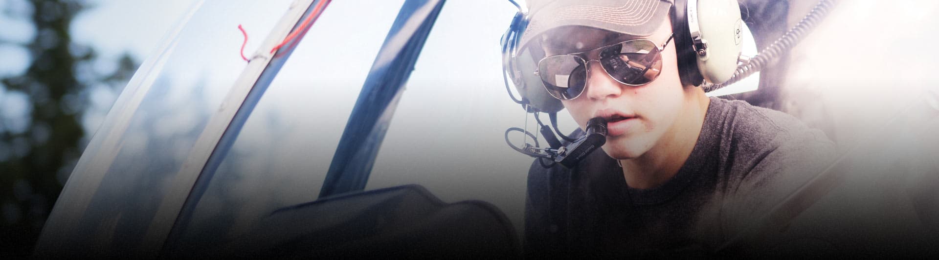 Estudiante piloto con casco y auriculares en la cabina de un helicóptero, programa Commercial Helicopter Foundations de Conestoga College