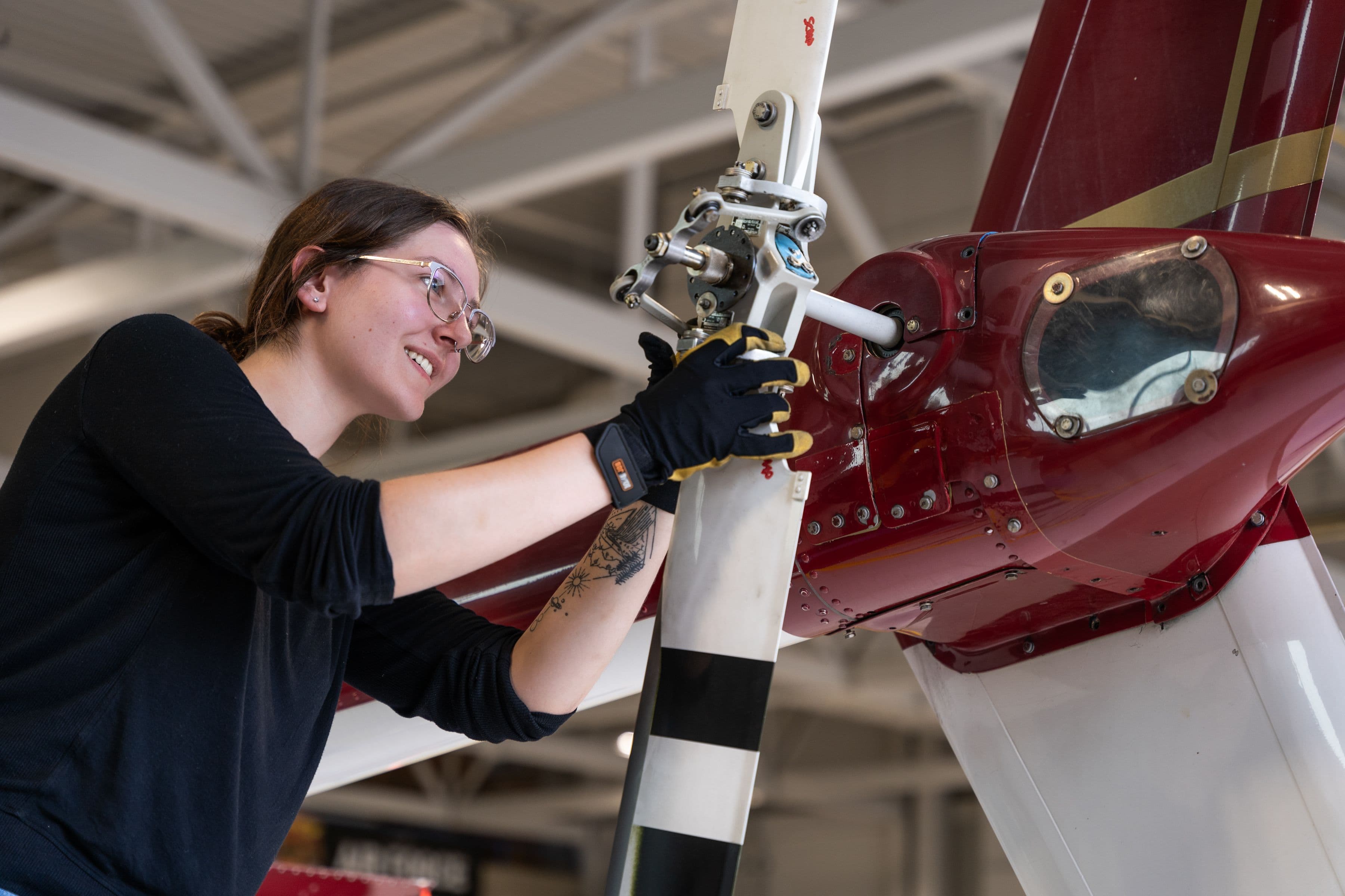 Estudiante con guantes de trabajo ajustando la hélice de una aeronave en un hangar, programa Aviation Technician - Aircraft Maintenance de Confederation College