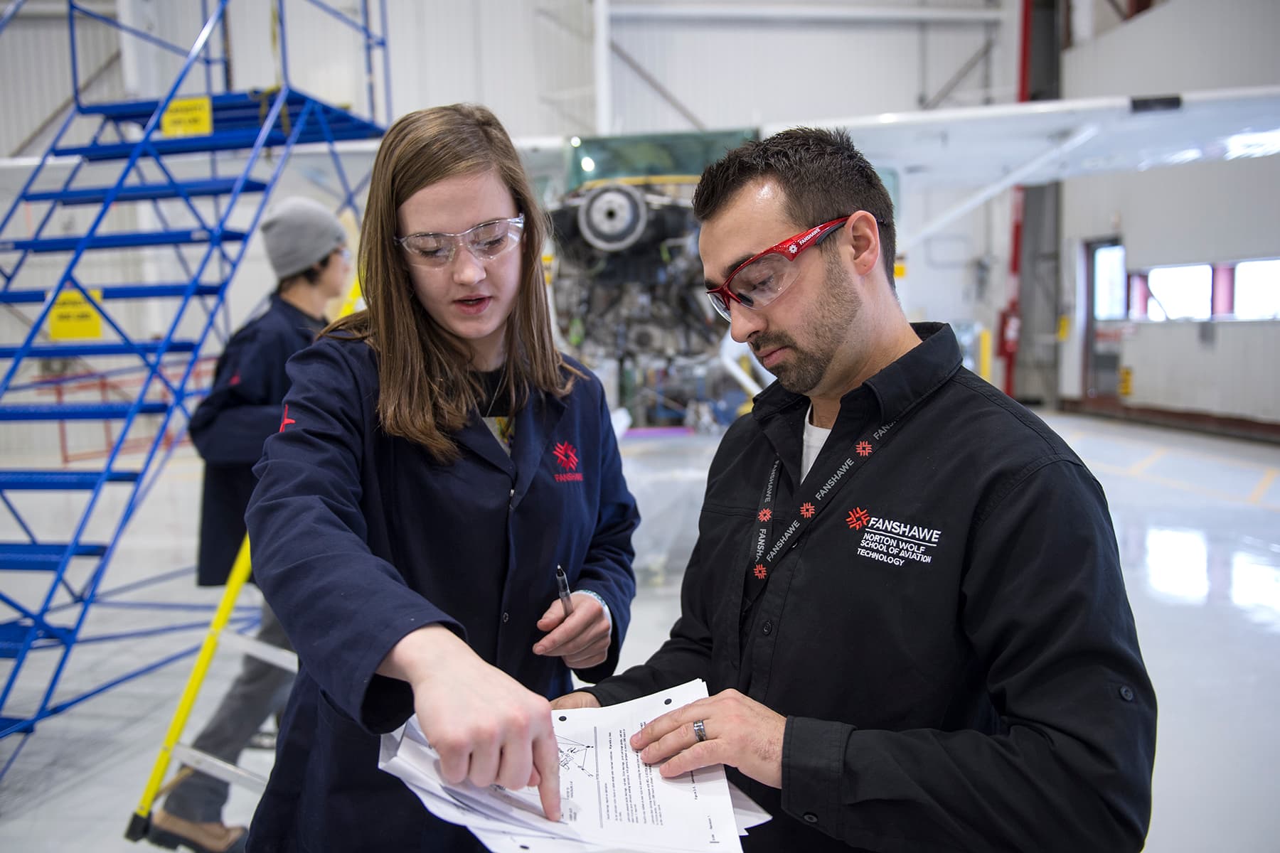 Instructor revisando información de aviación con un estudiante en un hangar, Fanshawe College