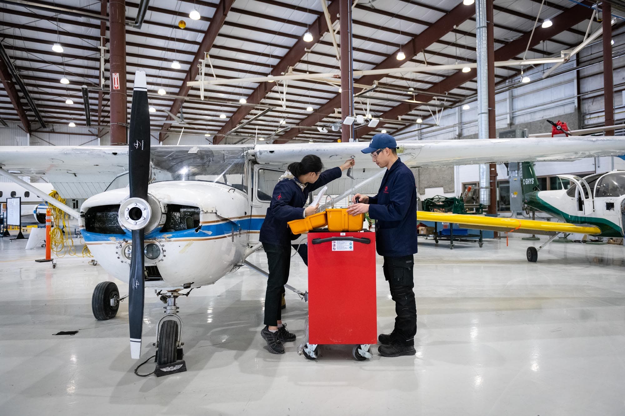 Estudiantes de Aviation Technician - Avionics Maintenance trabajando frente a una aeronave en el hangar Jazz, Fanshawe College