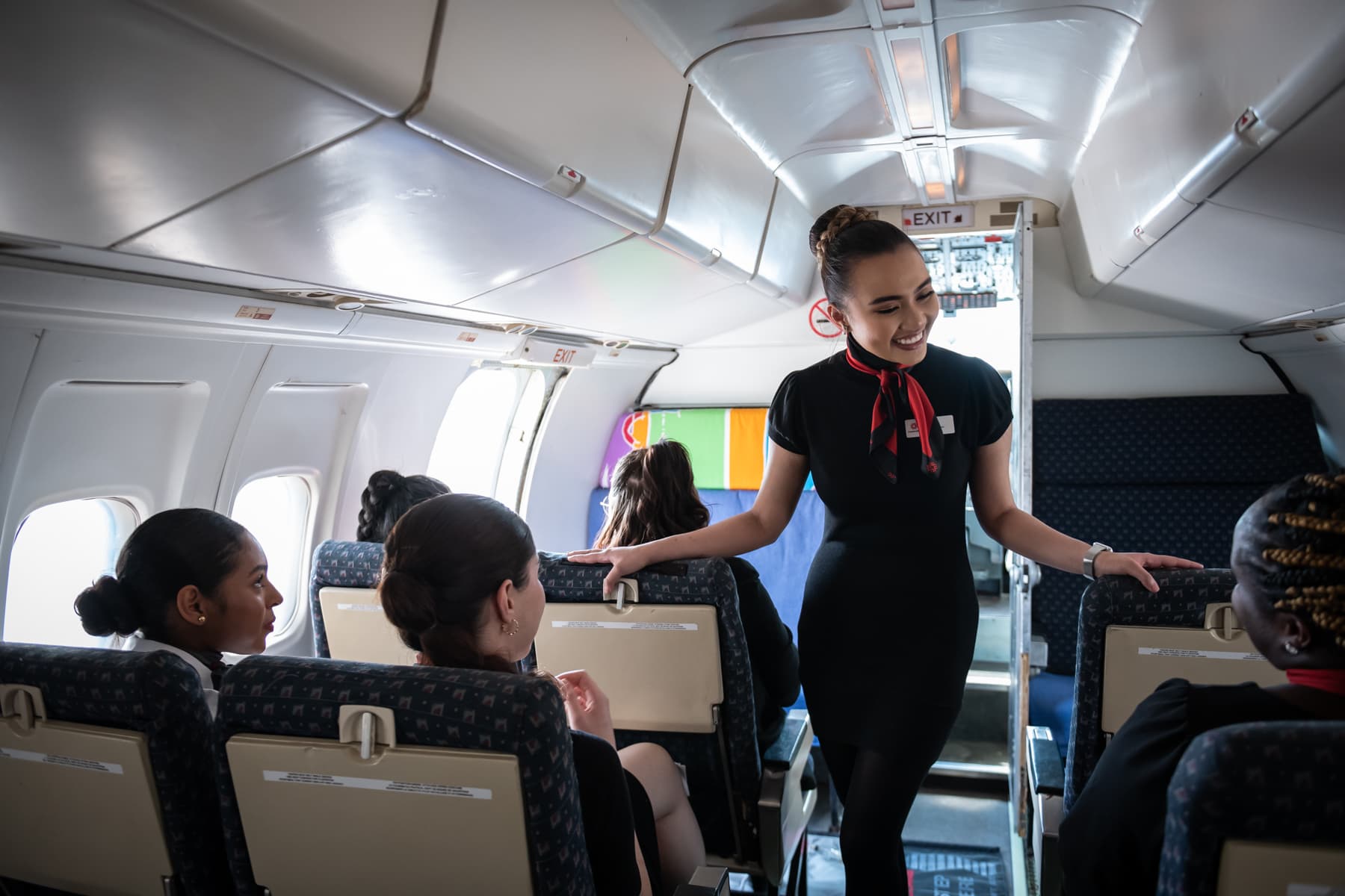 Estudiante de Flight Services de Fanshawe College atendiendo pasajeros en simulación de cabina