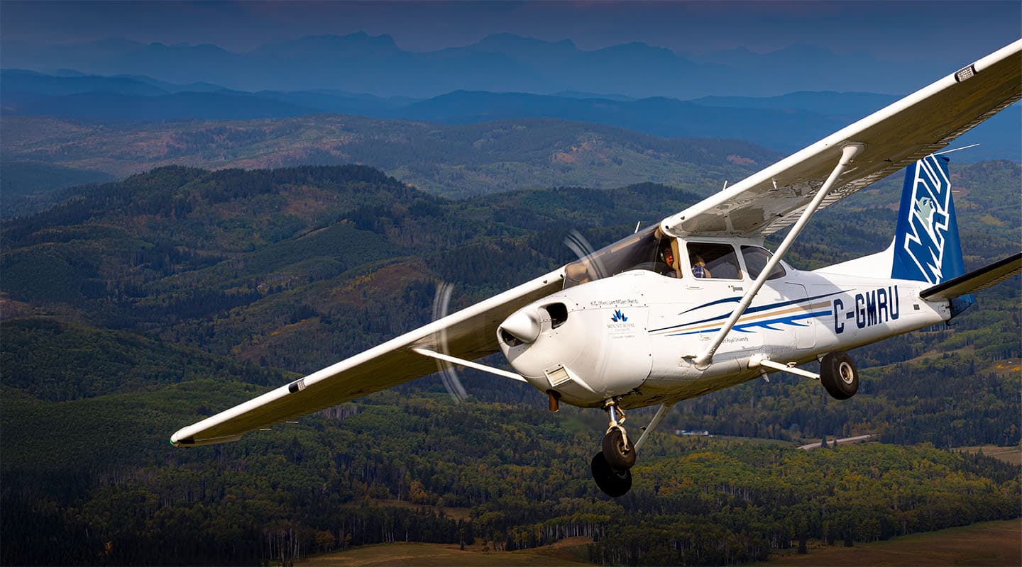 Avión con imagen de MRU volando frente a las Montañas Rocosas