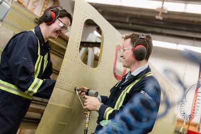 Estudiantes trabajando en la estructura de una aeronave en el Kelowna Aerospace Centre de Okanagan College