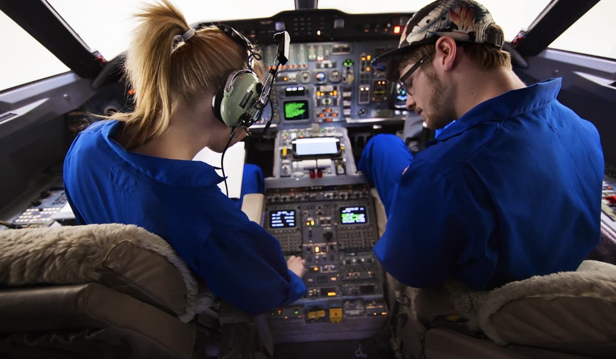 Estudiantes en la cabina de una aeronave revisando el panel de instrumentos, programa Avionics Technology de SAIT