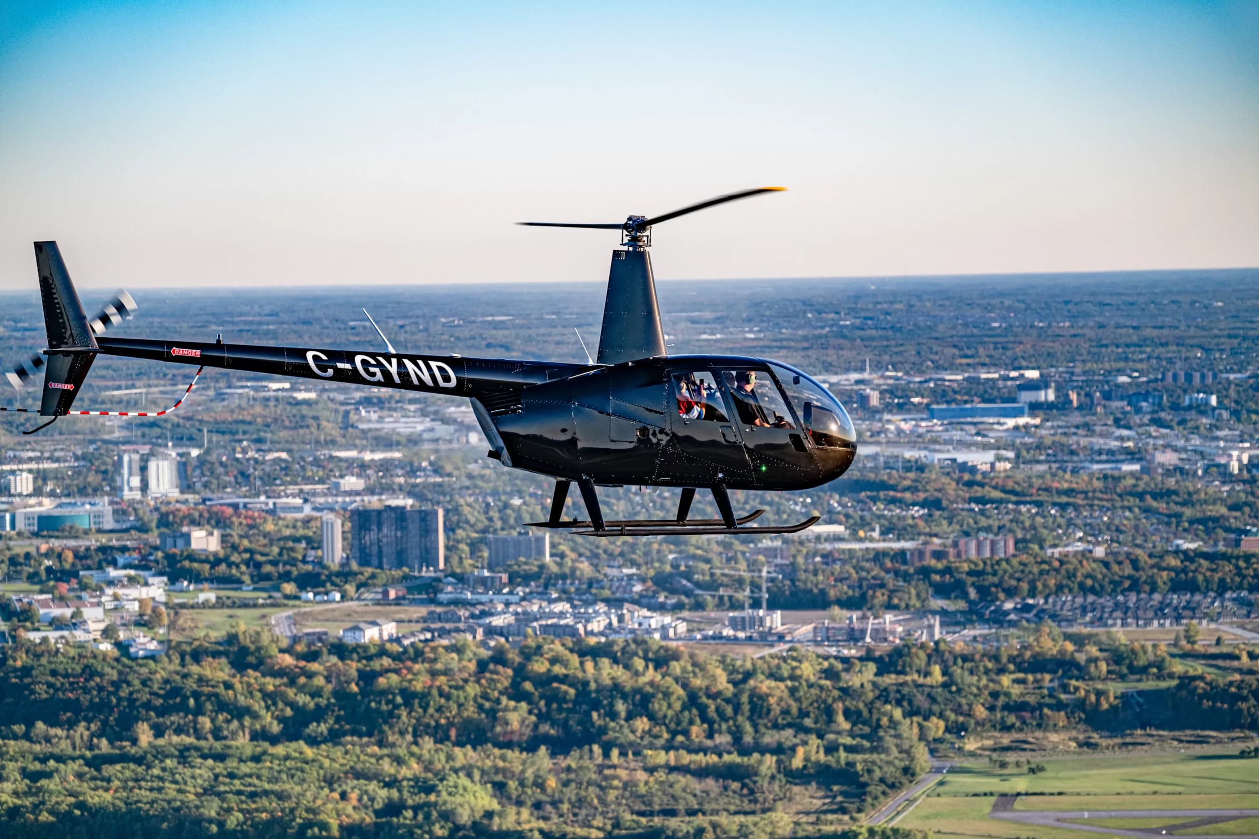 Helicóptero Robinson R44 en vuelo sobre la ciudad, programa EWA.1G de Select Aviation College