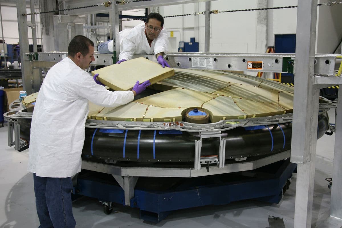 Técnicos ensamblando un componente aeroespacial en una fábrica