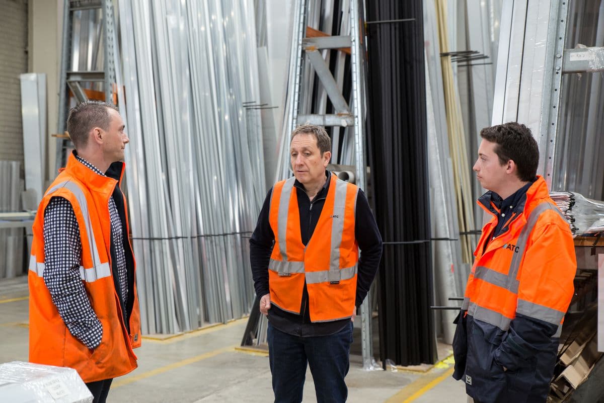 Equipo de trabajo con chalecos de seguridad conversando en un almacén industrial