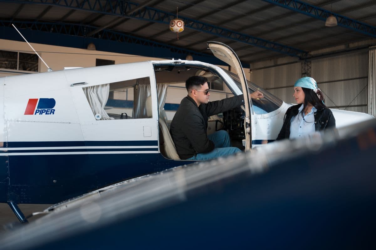 Piloto y copiloto conversando junto a una aeronave en un hangar