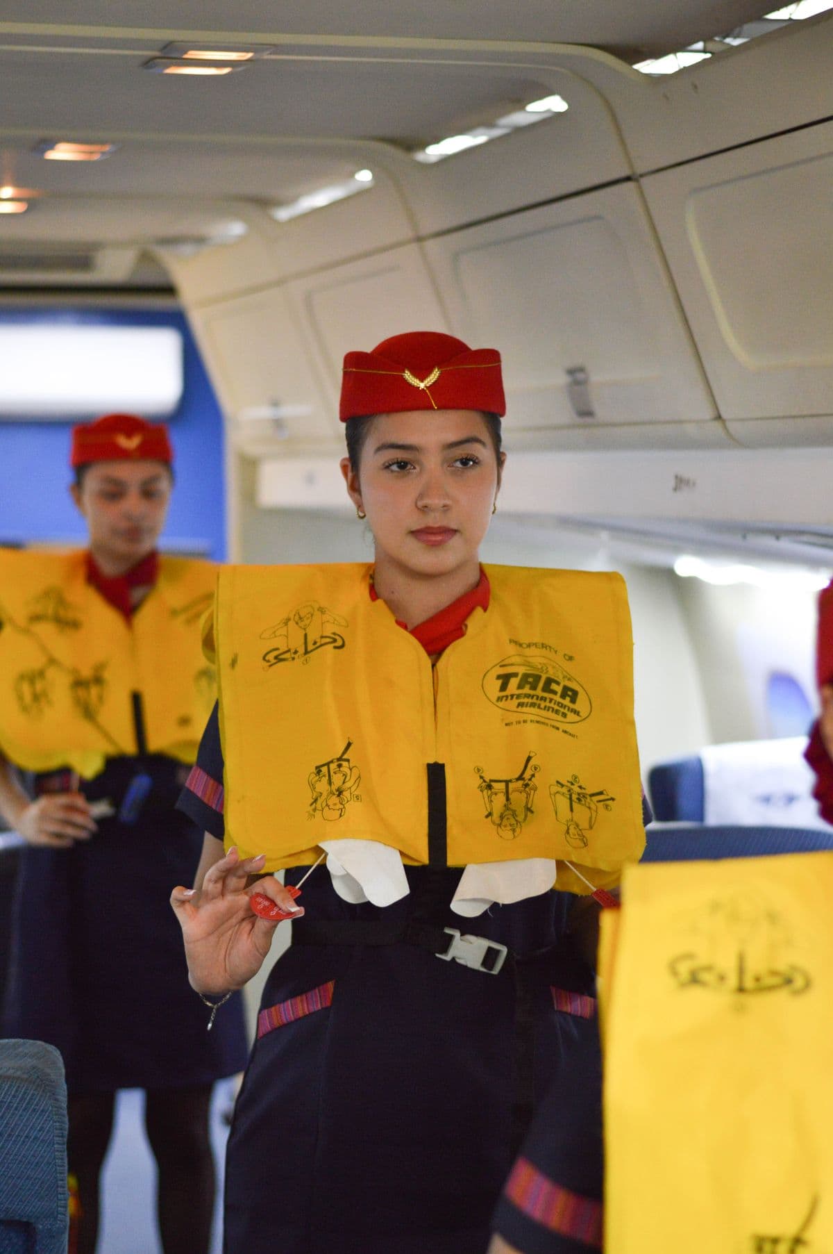 Auxiliar de vuelo mostrando el procedimiento de seguridad con un chaleco salvavidas