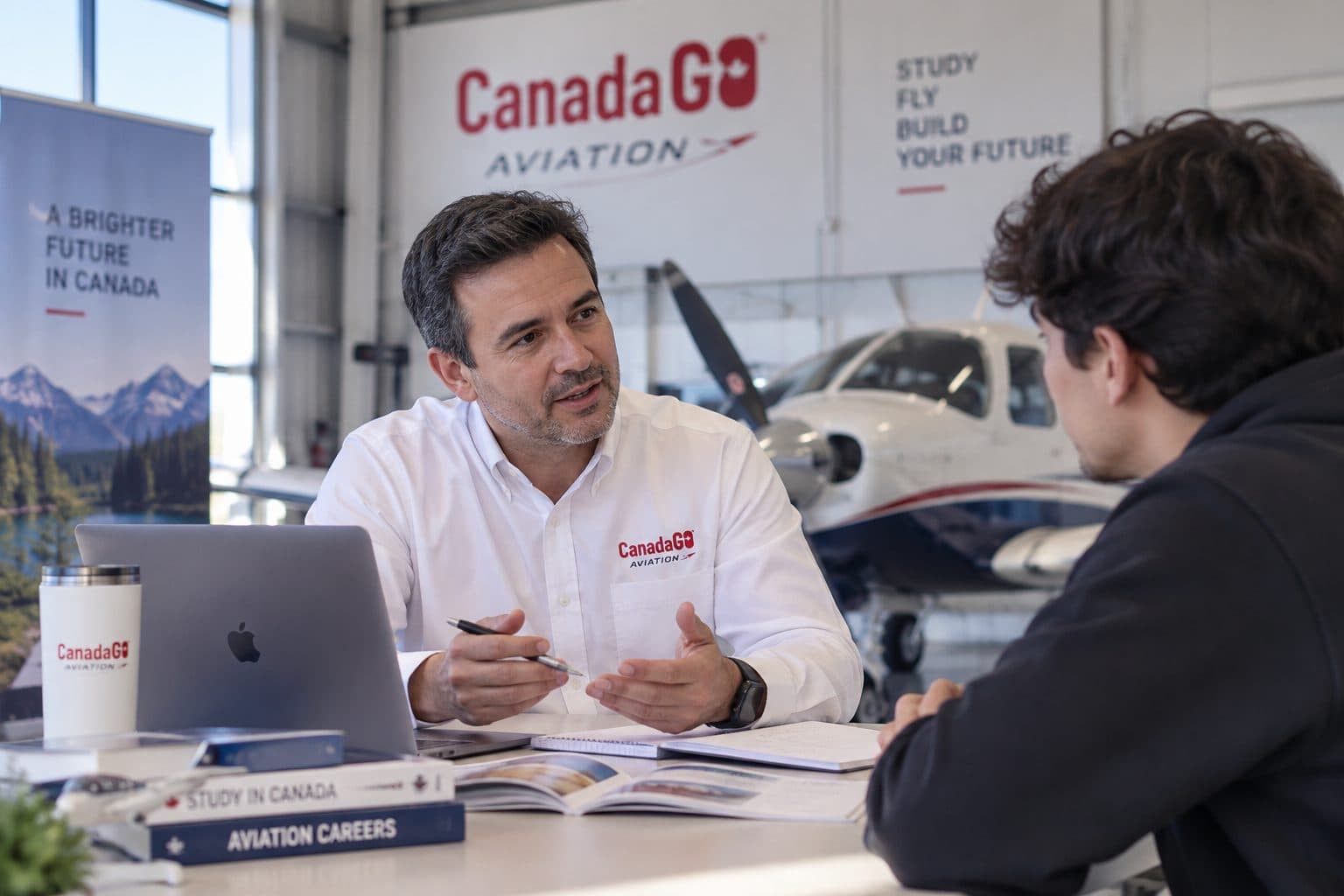 Asesor de Canada GO Aviation conversando con un estudiante en un hangar